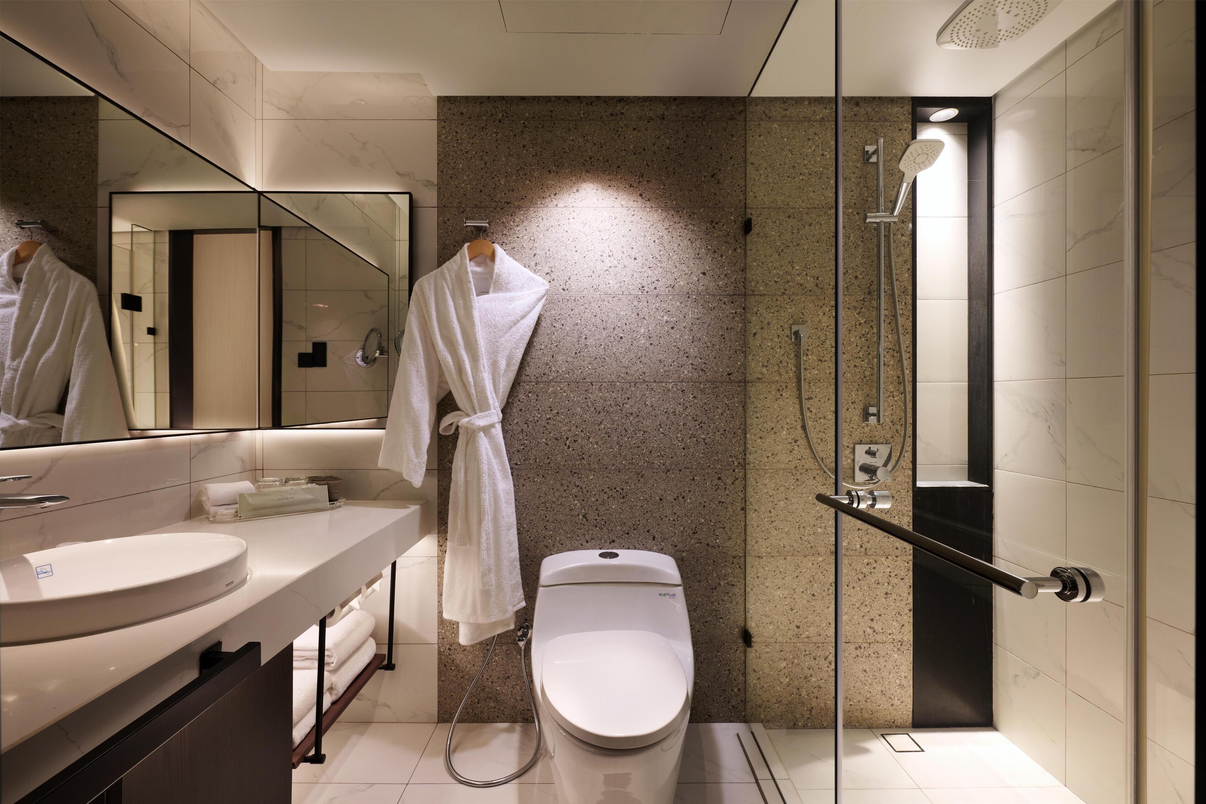 Un baño moderno con un lavamanos redondo, un inodoro y una zona de ducha con mampara de vidrio.