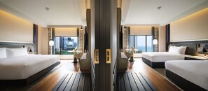 Habitación de hotel con dos camas, vistas a la ciudad y una zona de comedor con mesa y sillas.