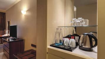 A hotel room with a minibar, a television, and a mirror.