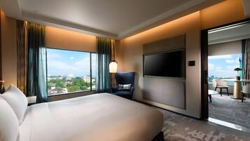 A hotel room with a large bed, a TV mounted on the wall, and a view of the city through the window.