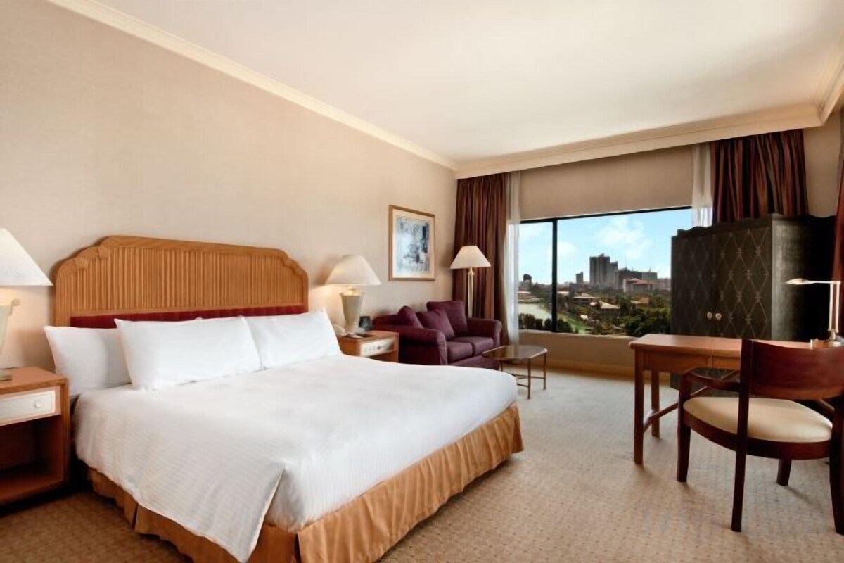 Una habitación de hotel con una cama grande, un escritorio, una silla y vistas a la ciudad.