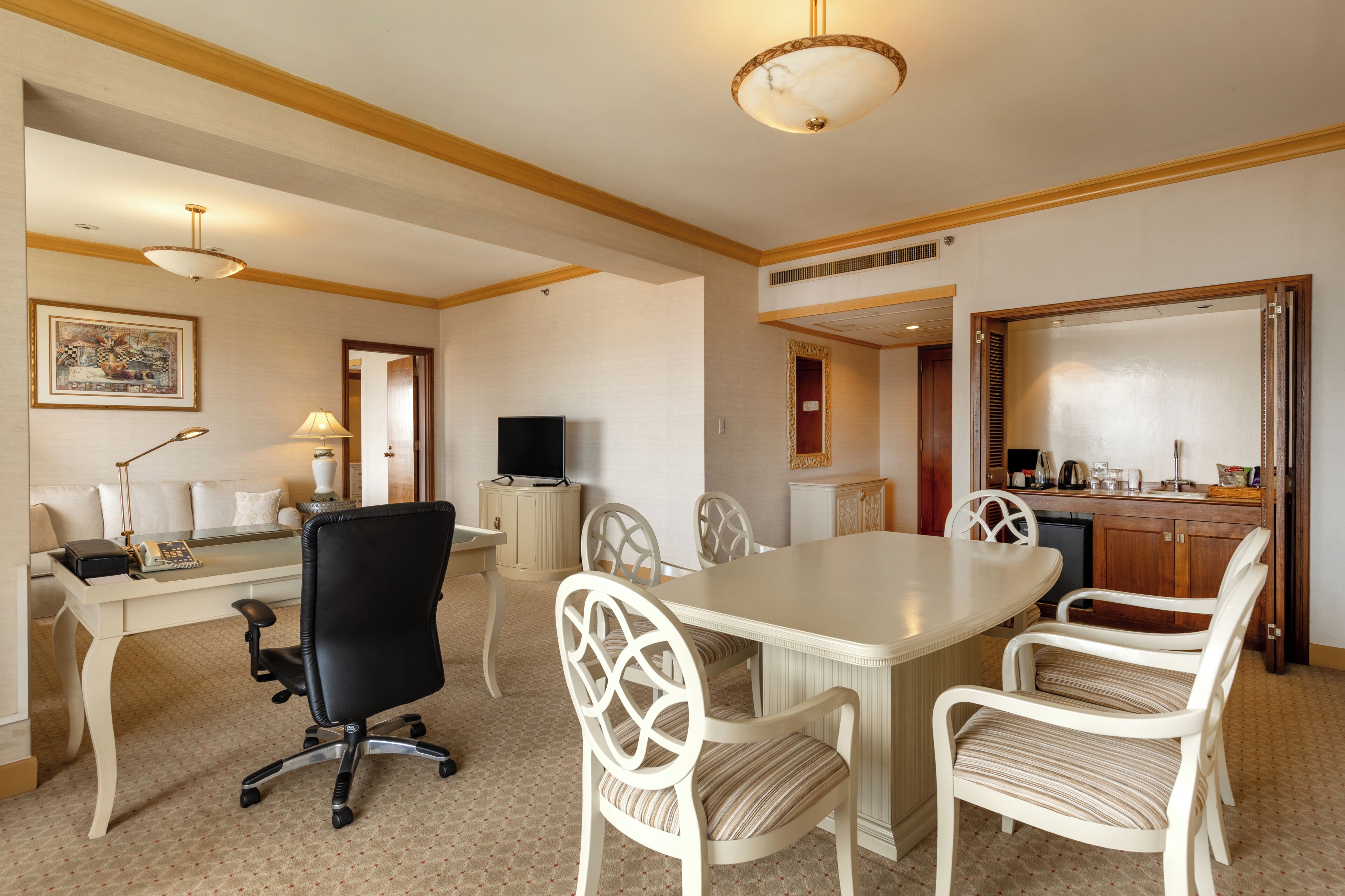 A conference room with a table, chairs, a desk with a computer, and a television.