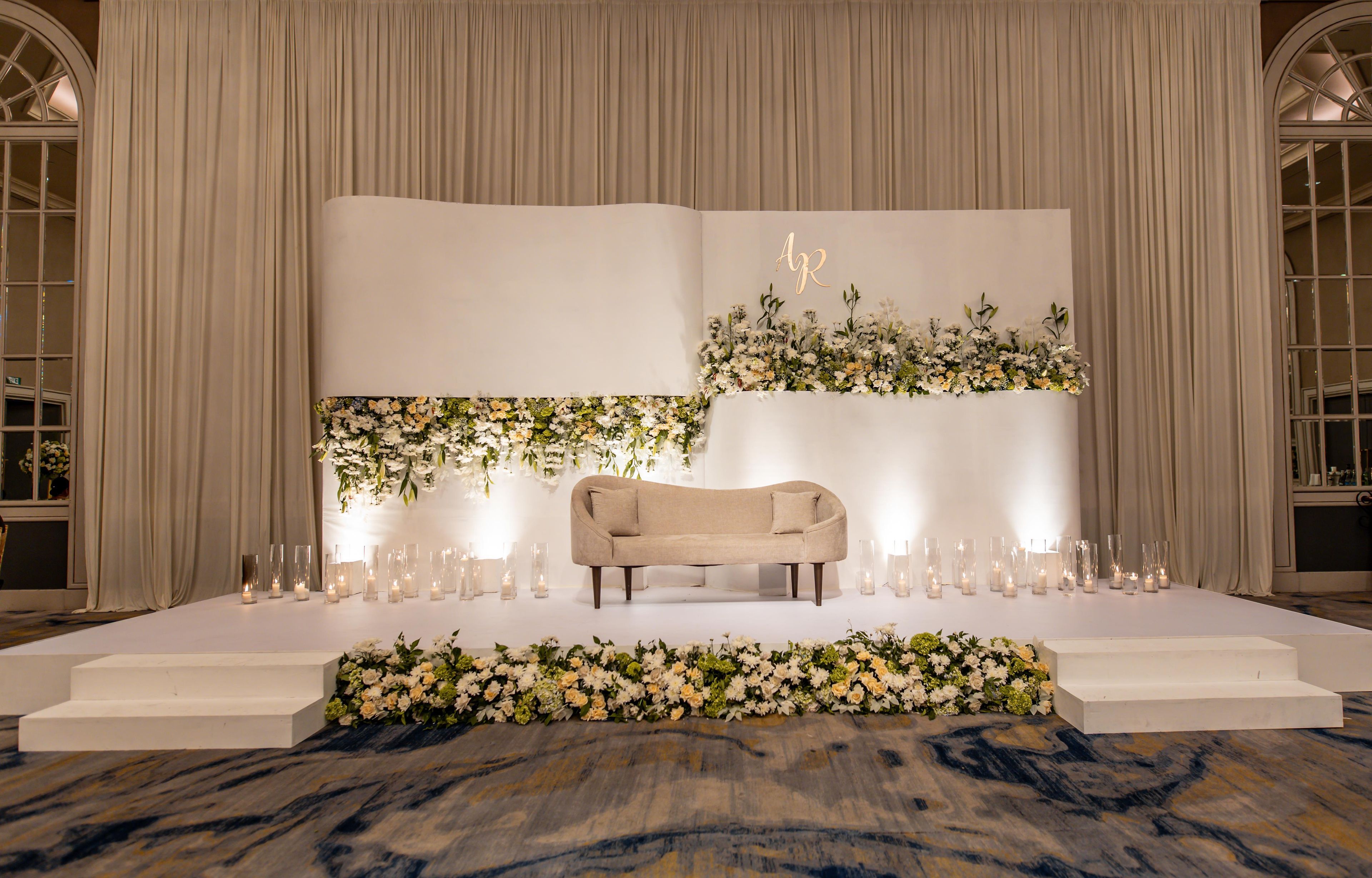 A stage with a sofa, floral arrangements, and candles.