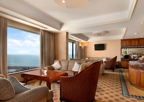 Amplia sala de estar con un gran ventanal con vista al mar, un espacio de descanso acogedor y una zona de bar con vistas.