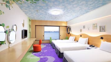 Ett hotellrum med två sängar, ett stort fönster med utsikt, ett tak med ett bladmotiv och en färgglad matta.