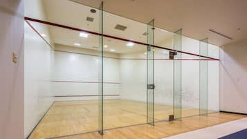 A squash court with glass walls and a wooden floor.