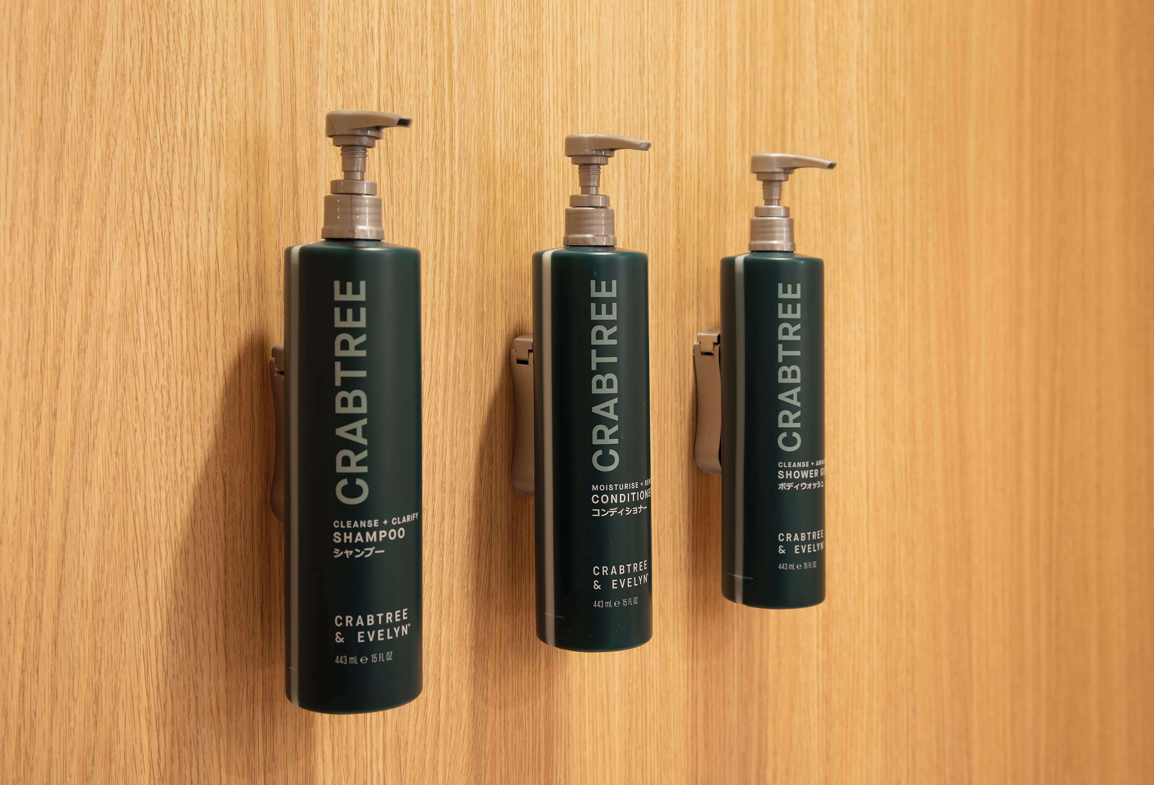 Three bottles of Crabtree & Evelyn shampoo on a wooden surface.