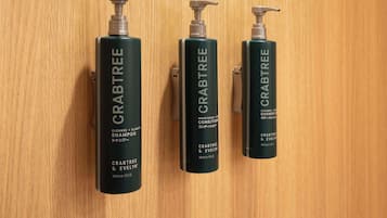 Three bottles of Crabtree & Evelyn shampoo on a wooden surface.