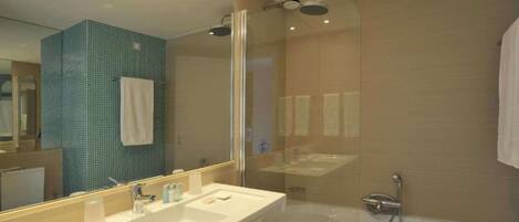 A modern bathroom with a large mirror, two sinks, a bathtub, and a shower.