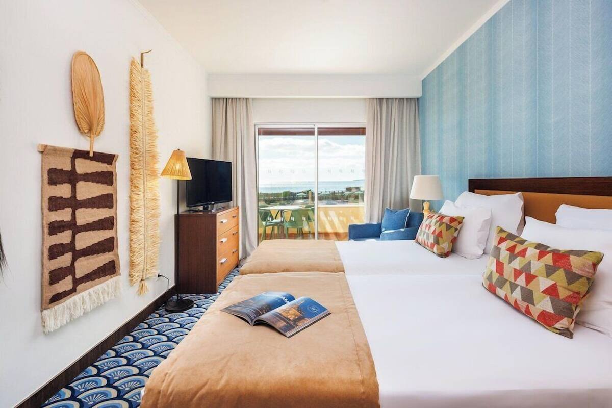 A hotel room with a large bed, a TV, a view of the outdoors, and a balcony.