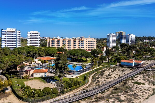 Un complejo turístico frente al mar con varias edificaciones, piscina y zona de playa.