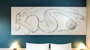 A hotel room with a large abstract painting on the wall, two bedside lamps, and a neatly made bed with white linens. - ibis Liège Centre Opéra (Liege)