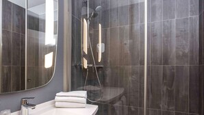 A modern bathroom with a large mirror, a sink, and a shower enclosure. - ibis Liège Centre Opéra (Liege)