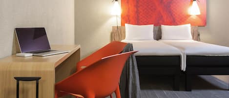 Ein Hotelzimmer mit Bett, Schreibtisch, Stuhl und Koffer.