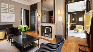 A spacious room with a fireplace, striped sofas, and a large mirror. - Pavillon de la Reine & Spa, Place des Vosges (Paris)
