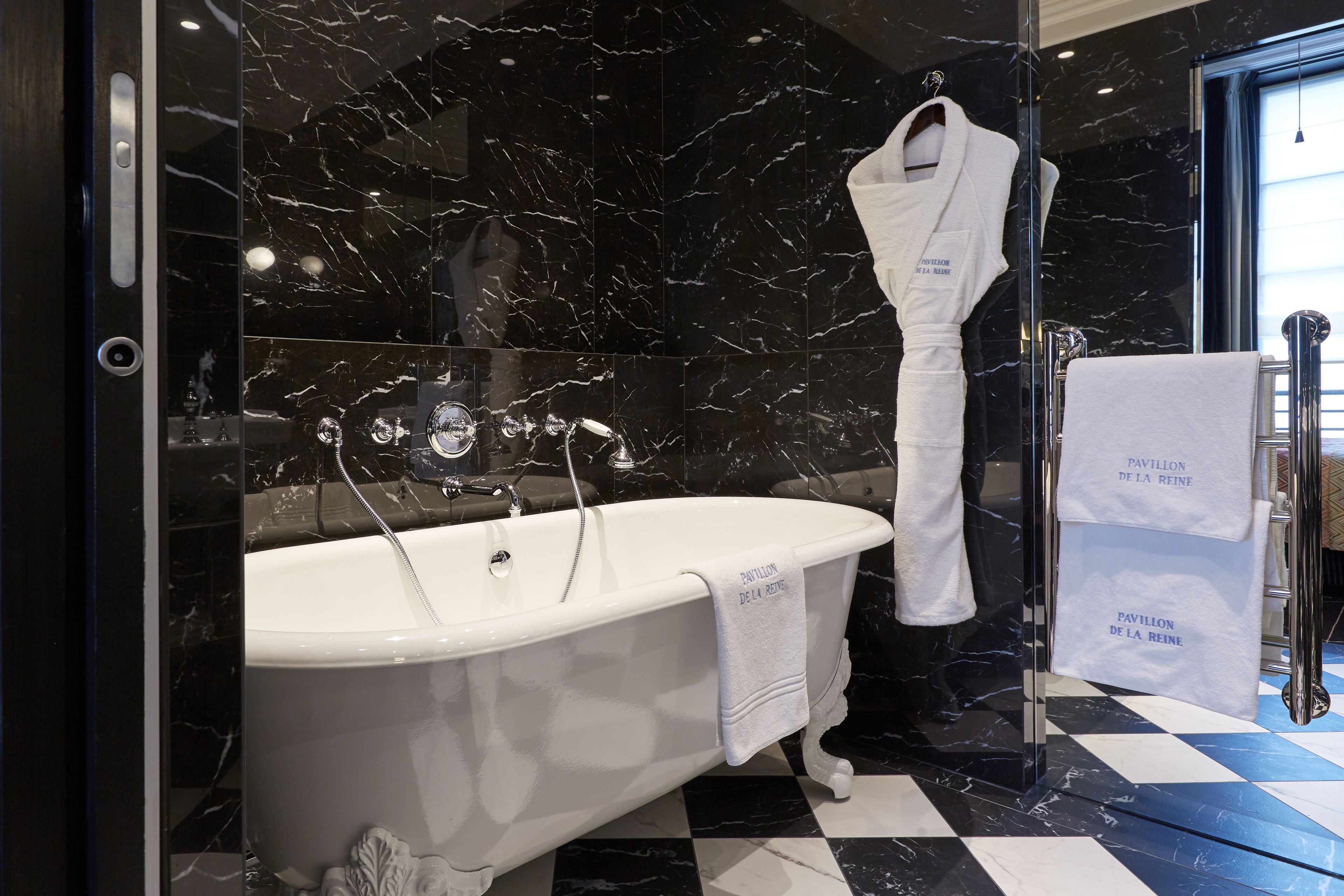 A modern bathroom with a freestanding bathtub, black and white checkered floor, and a towel rack with a white towel.