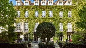 A building with a covered courtyard, large windows, and a central tree. - Pavillon de la Reine & Spa, Place des Vosges (Paris)