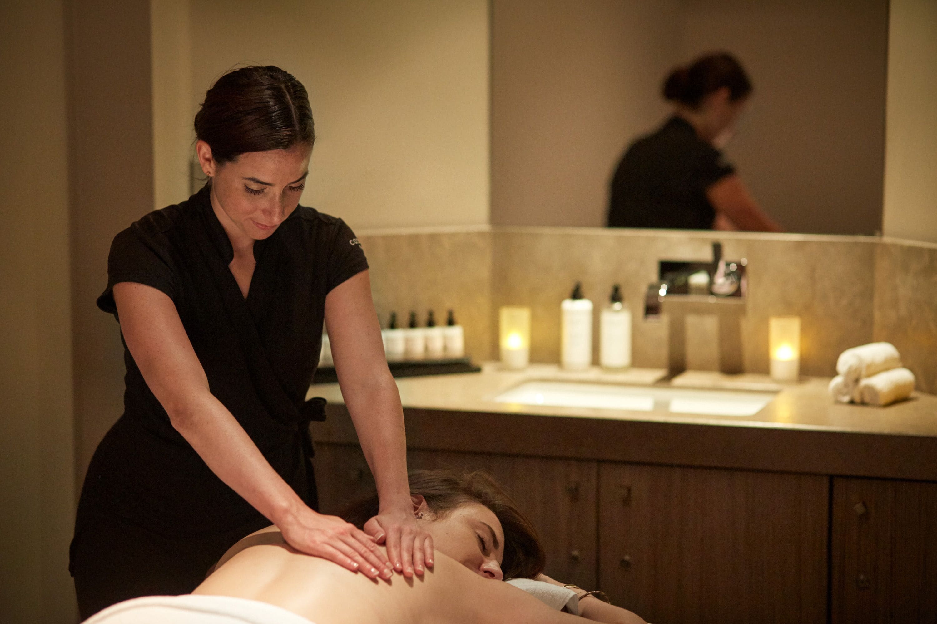 Sesión de masoterapia en un spa, con mostrador de madera y velas.