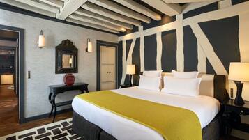 A hotel room with a large bed, a wooden ceiling, a mirror, and a desk with a lamp.