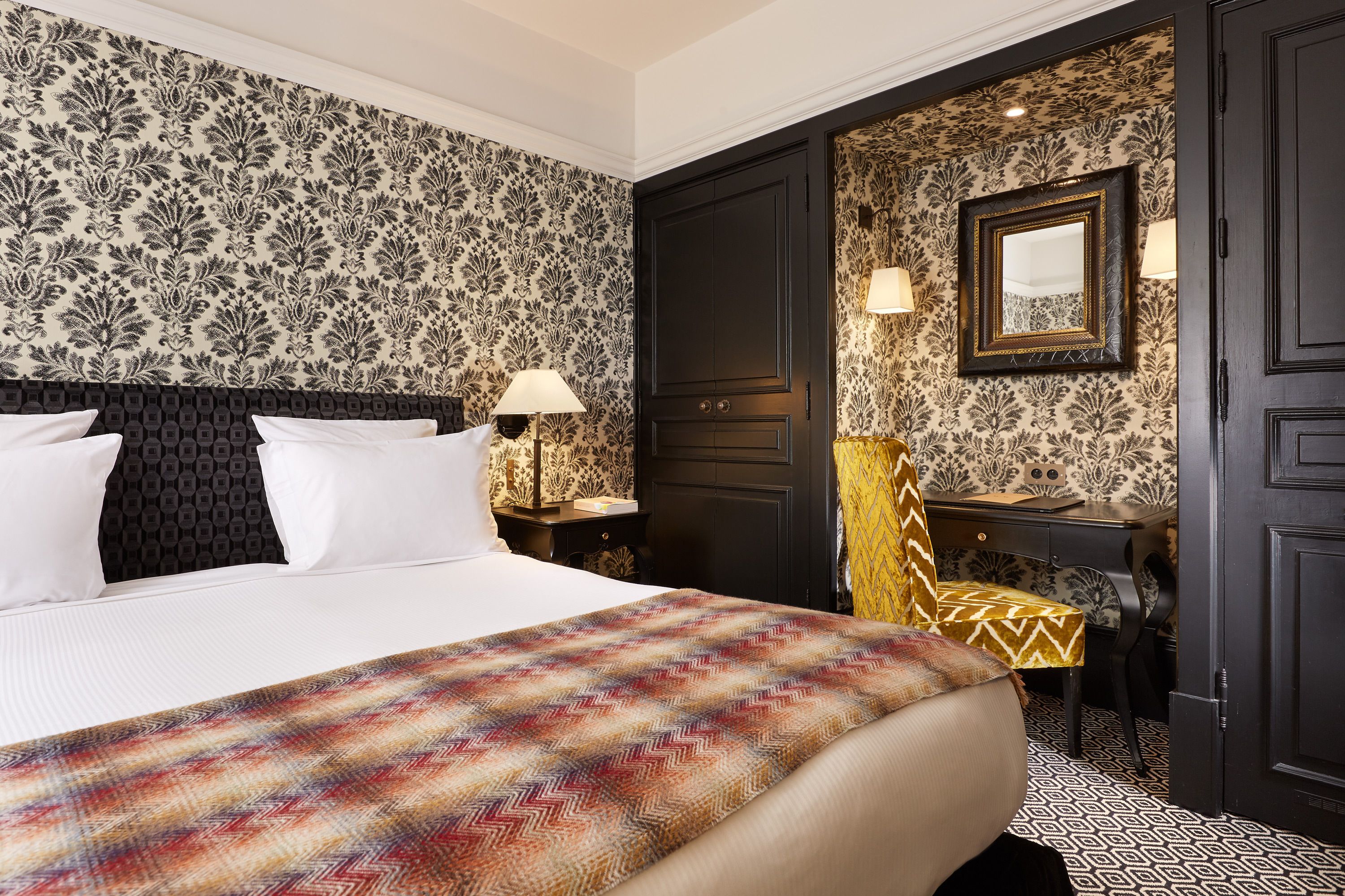 A hotel room with a large bed, a desk, and a chair.