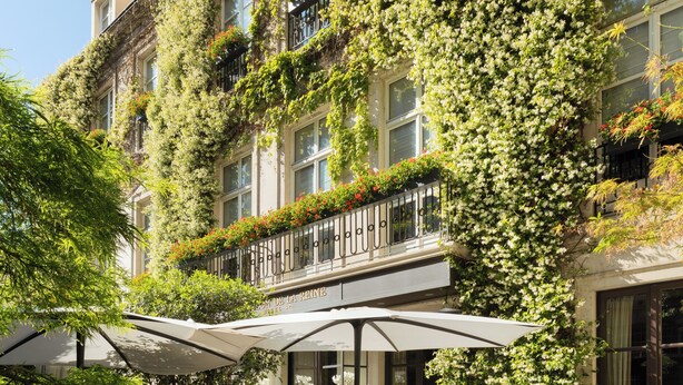 An outdoor cafe with tables and chairs, surrounded by a building with ivy-covered balconies. - Pavillon de la Reine & Spa, Place des Vosges (Paris)