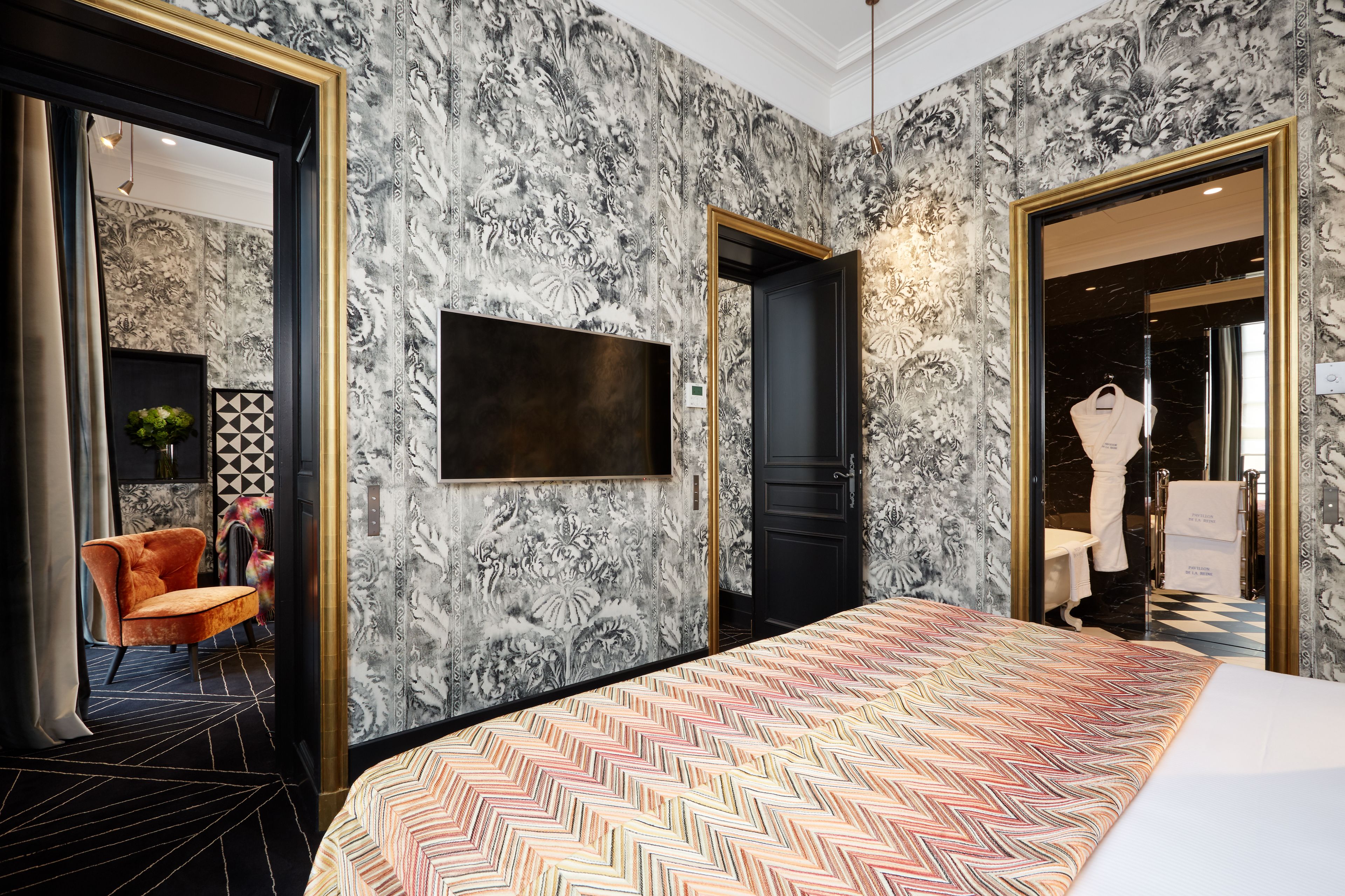 A hotel room with a large bed, a TV mounted on the wall, and a wardrobe with a mirror.