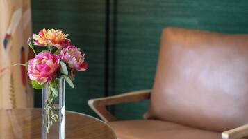 A clear view of a room with a round wooden table, a vase with flowers, a brown leather sofa, and a floor lamp.
