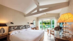 A hotel room with a large bed, a desk, a chair, a lamp, and a balcony with a table and chairs. - La Réserve Albi - Hotel Restaurant (Albi)