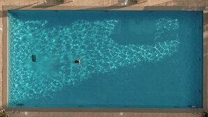 A rectangular swimming pool with clear blue water and a person swimming. - La Réserve Albi - Hotel Restaurant (Albi)