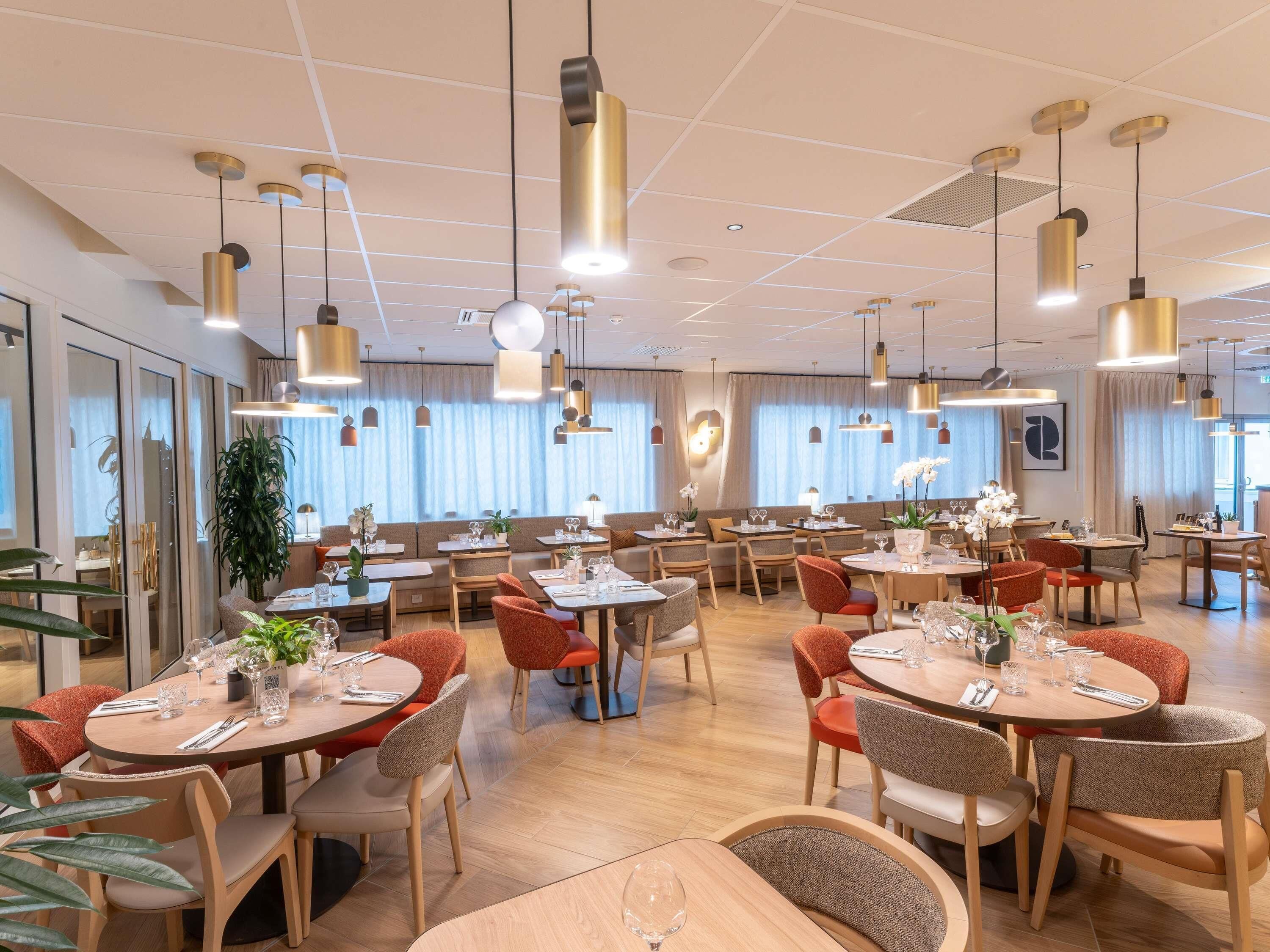Ein modernes Restaurant mit mehreren Essbereichen, darunter Sitzecken und Tische mit Stühlen.