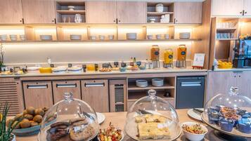 Un buffet proposant une variété de plats et de boissons, notamment des biscuits, des pâtisseries et un coin café.