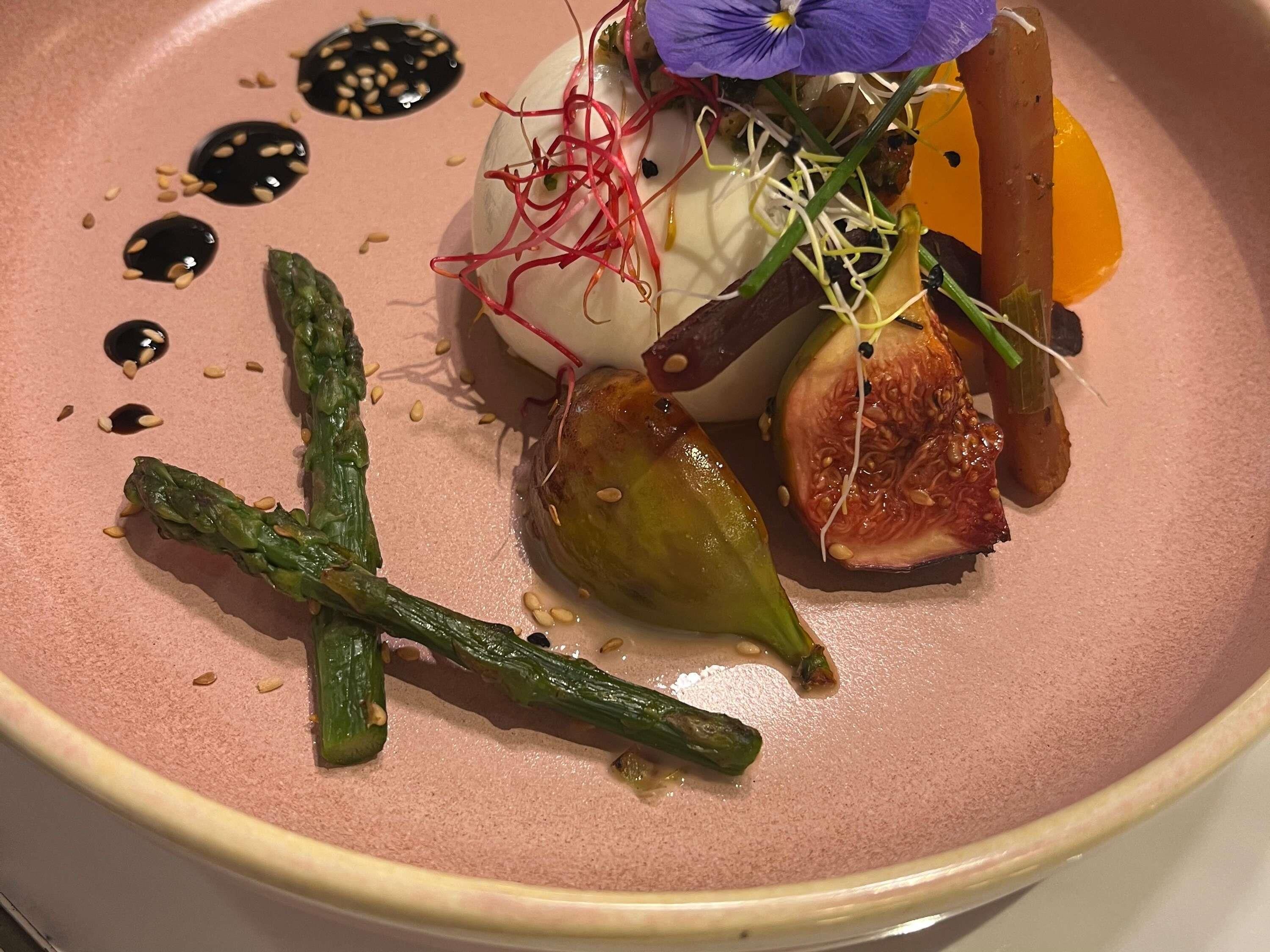 Un plato con varias verduras y una flor púrpura como decoración.