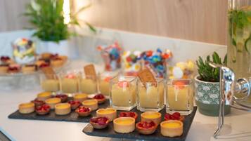 A dessert table with various pastries and small cakes, including tarts and custard cups, arranged on a slate board.