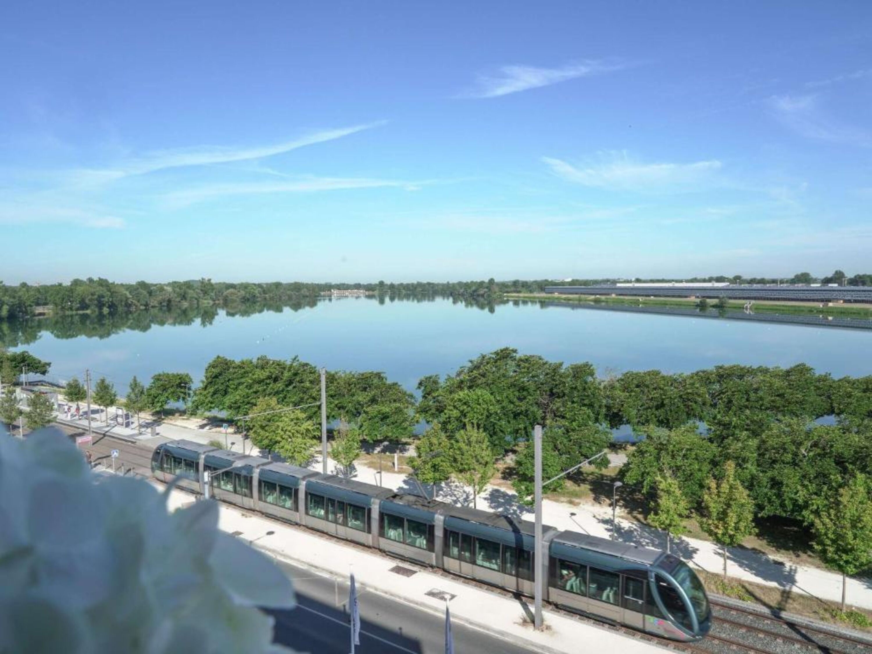A modern train station with a view of a calm lake and lush greenery.