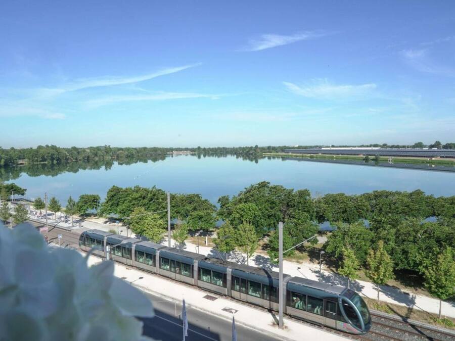 A modern train station with a view of a calm lake and lush greenery.