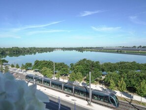 Una estación de tren moderna con vistas a un lago tranquilo y abundante vegetación.