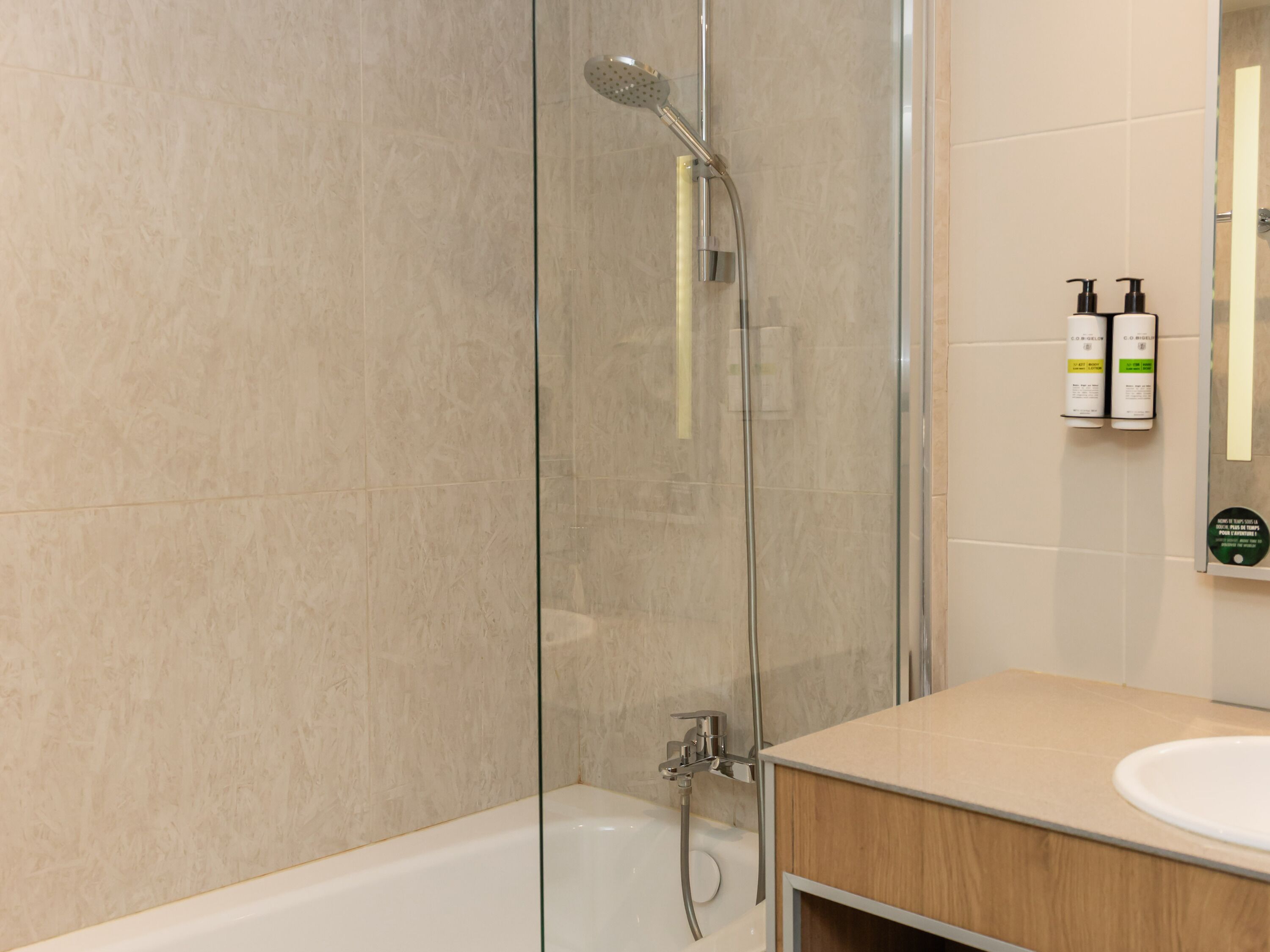 Un baño moderno con cabina de ducha de vidrio, una bañera y un tocador de madera con lavamanos.