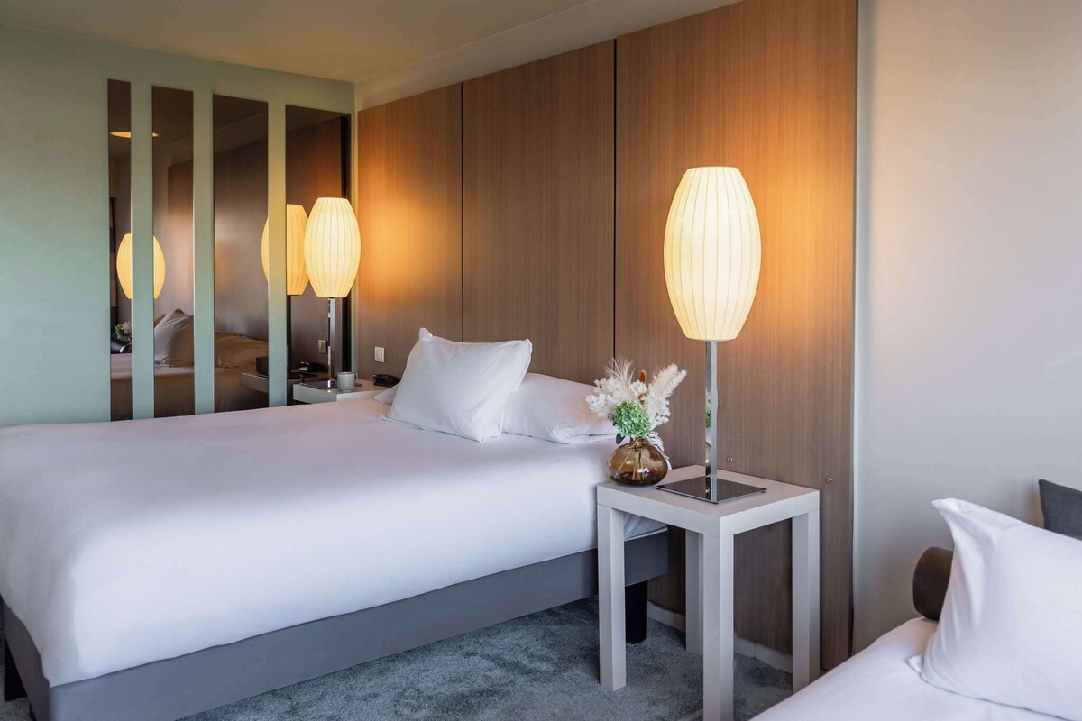 Una habitación de hotel con una cama grande, dos mesitas de noche y un espejo.