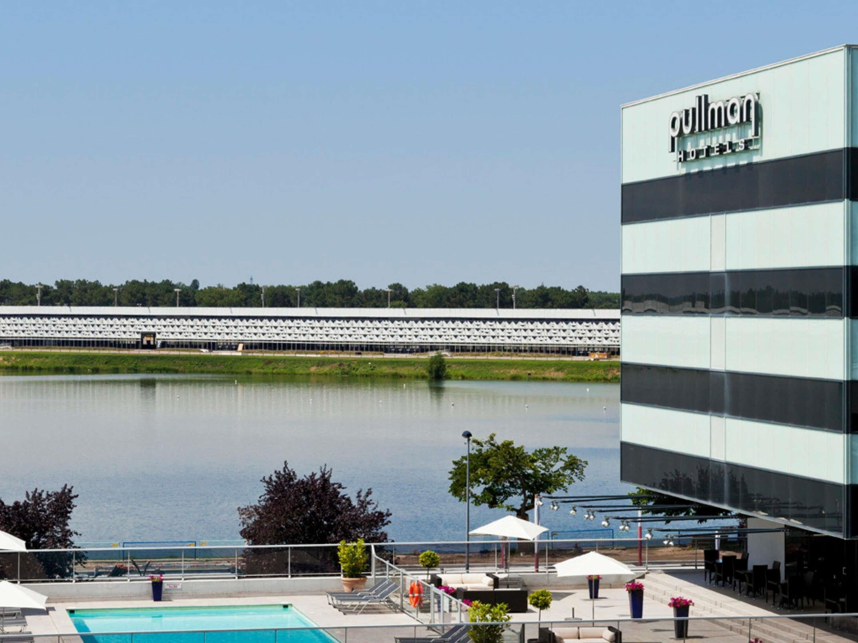A hotel with a pool, outdoor seating, and a view of a large body of water.