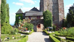 A historic building with a tower, a covered walkway, and well-maintained gardens. - ibis Brive Centre (Brive-la-Gaillarde)