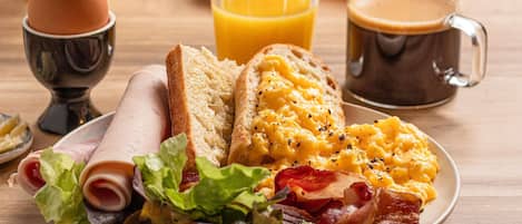 Un plato de desayuno con huevos, tocino, tostadas y un vaso de jugo de naranja.