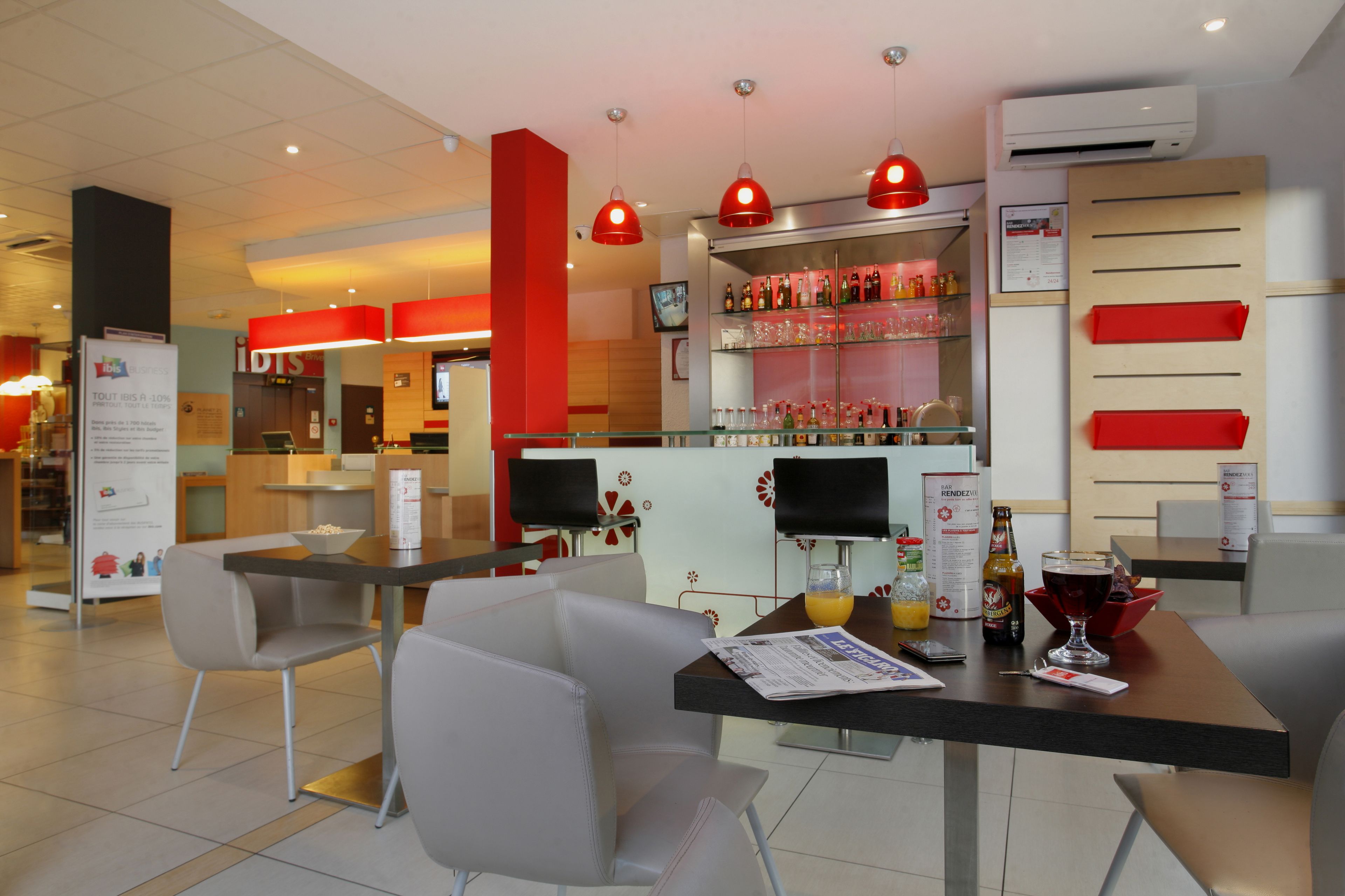 A modern restaurant with a bar area, seating with tables and chairs, and a variety of food and drink items on display.