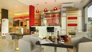 A modern restaurant with a bar area, seating, and a view of the city. - ibis Brive Centre (Brive-la-Gaillarde)