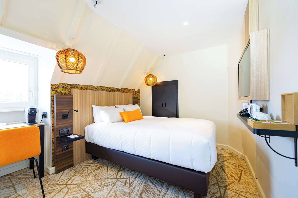 Una habitación de hotel moderna con una cama grande, un escritorio y un armario.