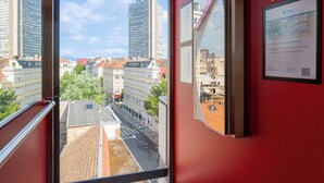 A corridor with a large window offering a view of tall buildings and a clear sky. - Best Western Mulhouse Salvator Centre (Mulhouse)
