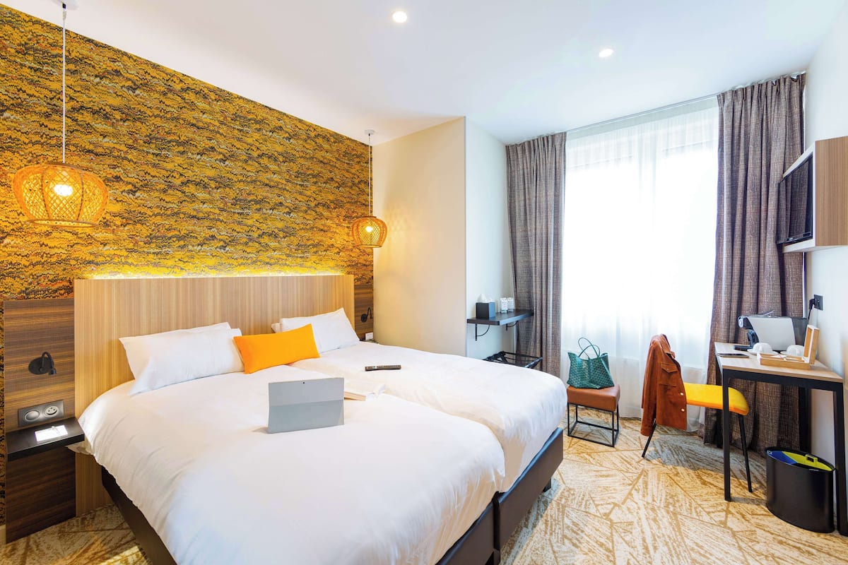 Habitación de hotel con una cama grande, un escritorio con computadora, una silla, una mesita y un televisor.