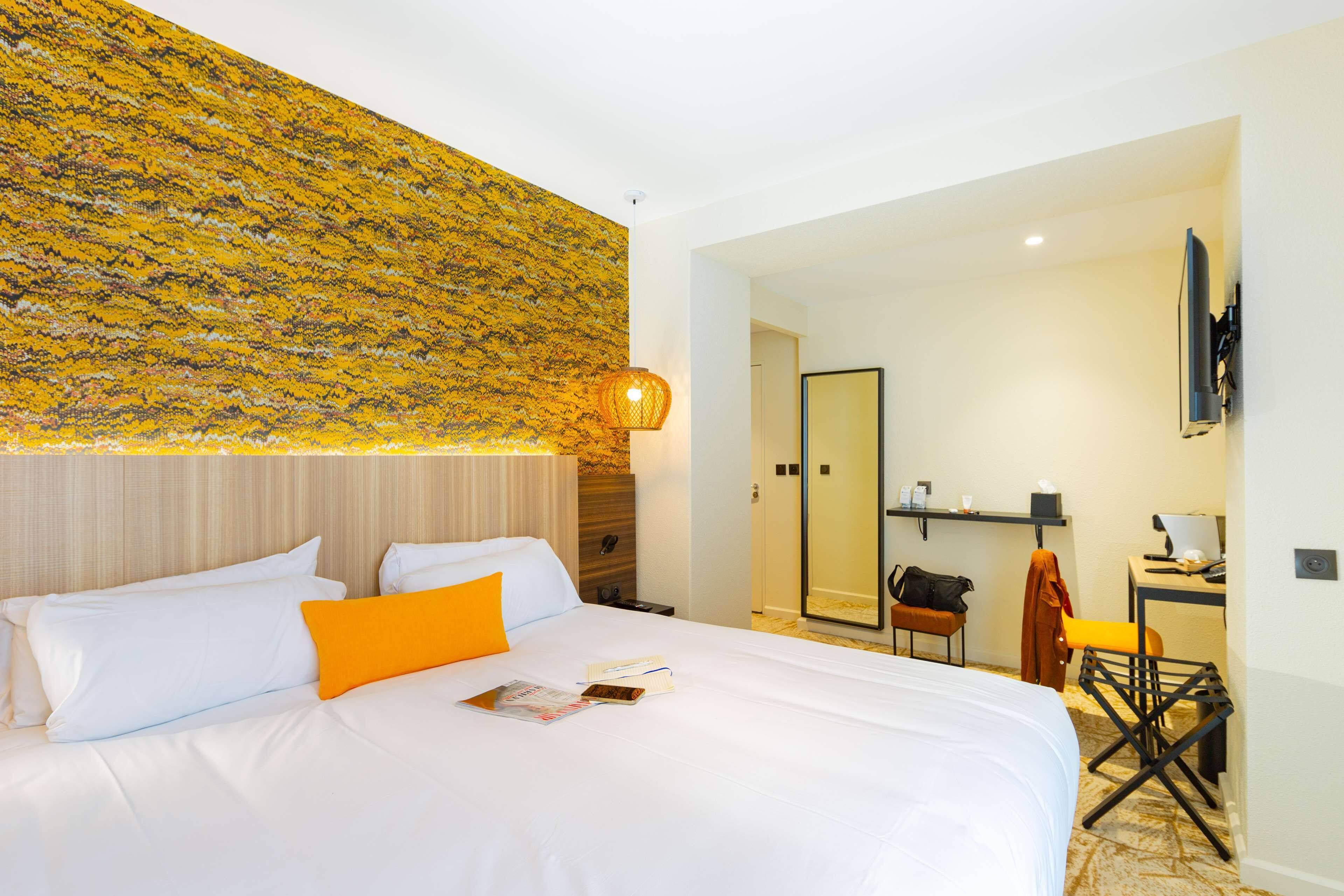 A hotel room with a bed, a desk, and a bathroom.