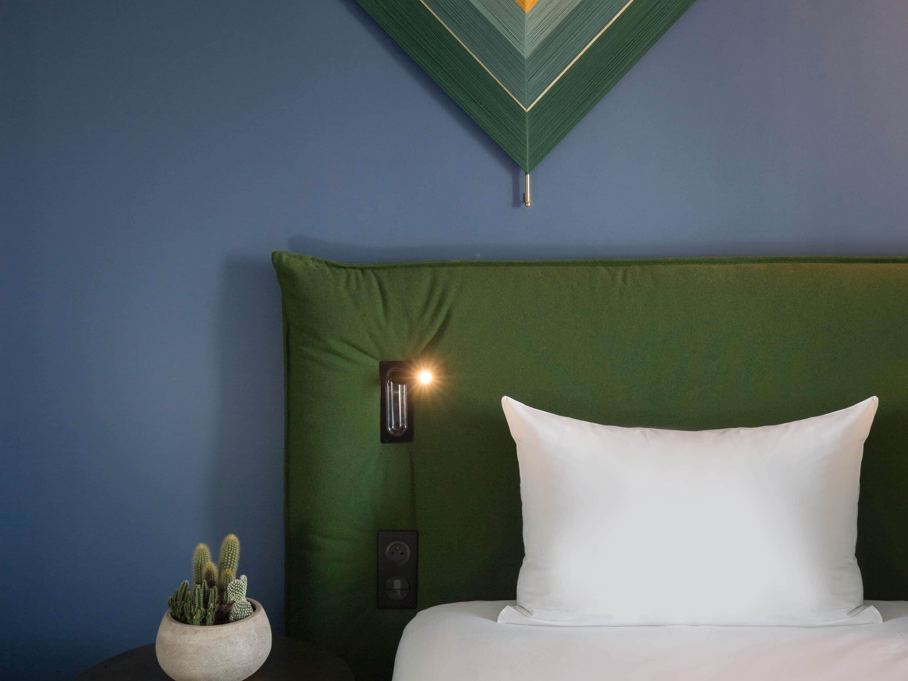 A neatly made bed with a white pillow and a green headboard.