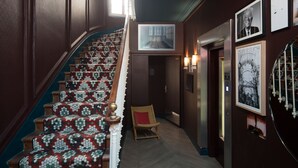 A staircase with patterned carpet, a chair, and framed pictures on the walls. - ibis Styles Paris Nation Cours de Vincennes (Paris)