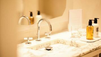 A bathroom with a marble sink, a mirror, and two bottles of liquid soap.